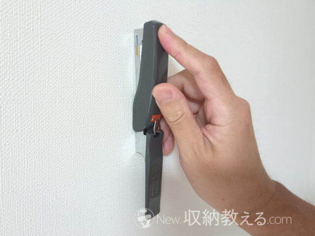 ステープラーで石膏ボード壁にステープルを打つ様子